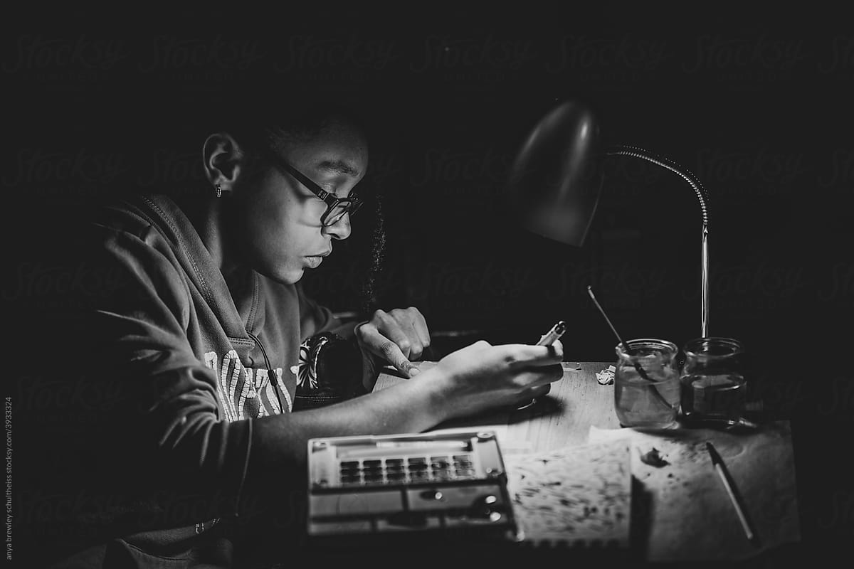 Teenager working on art for school by lamplight