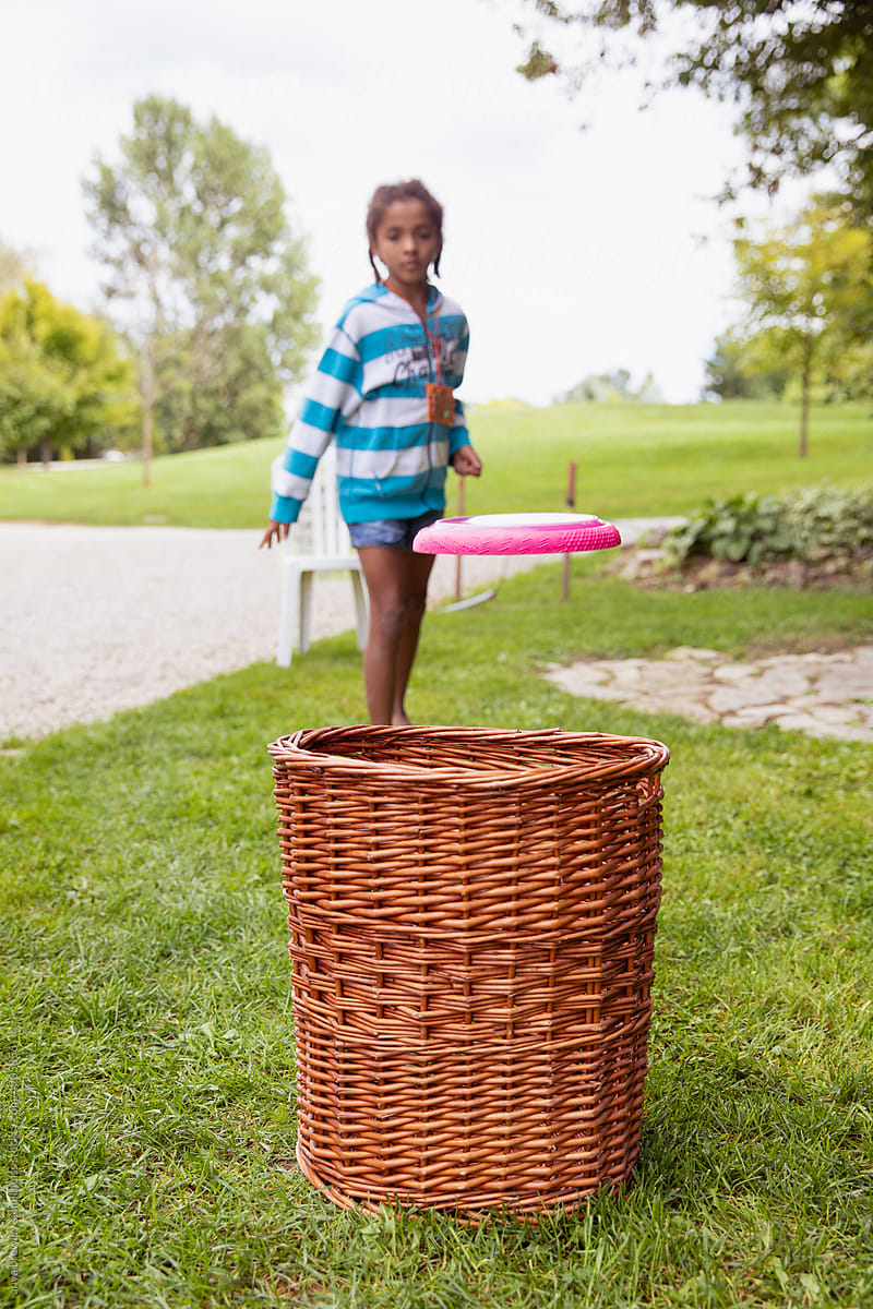 Child aiming and tossing a frisbee into a basket