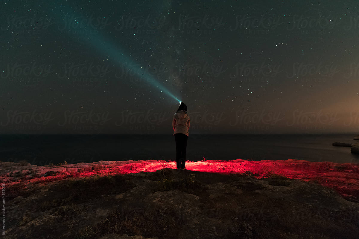 Standing woman with head torch looking at the stars