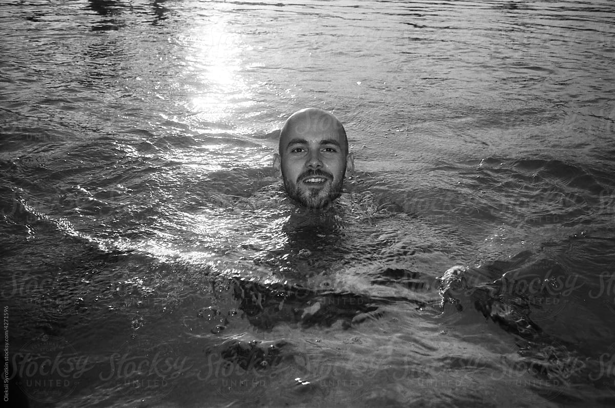Black and white photo of cheerful boy swimming in pool
