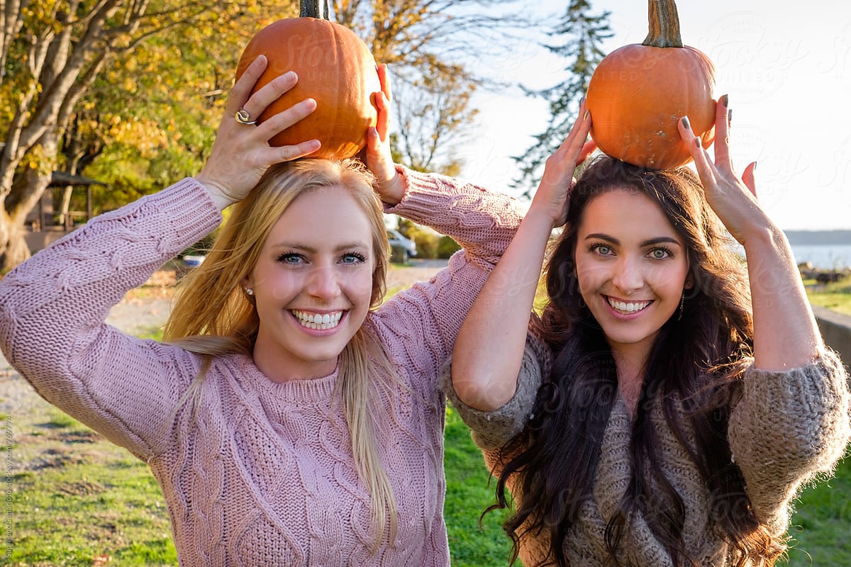 Female friends holding pumpkins celebrating Halloween