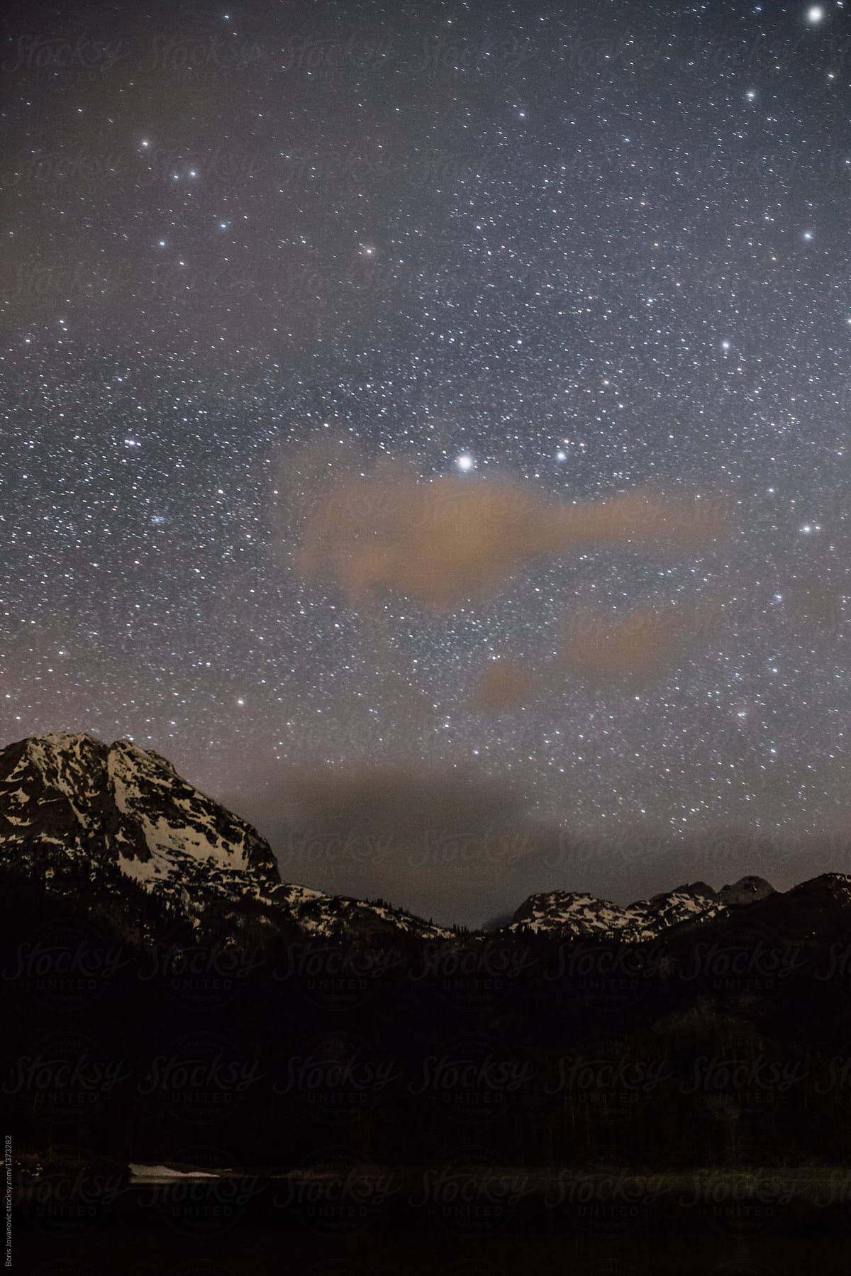 Rocky mountain peak covered with snow under the sky full of stars
