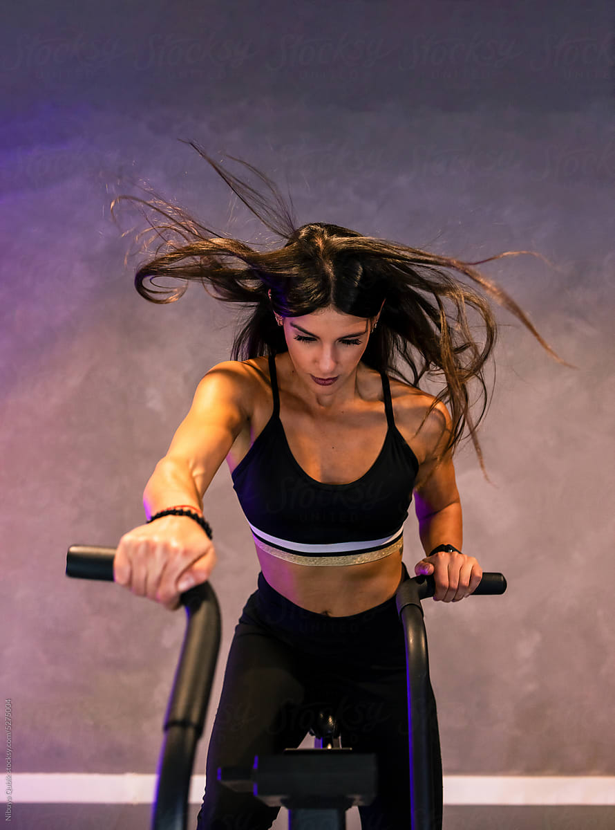 fit sportswoman riding on air bicycle during cardio training in gym