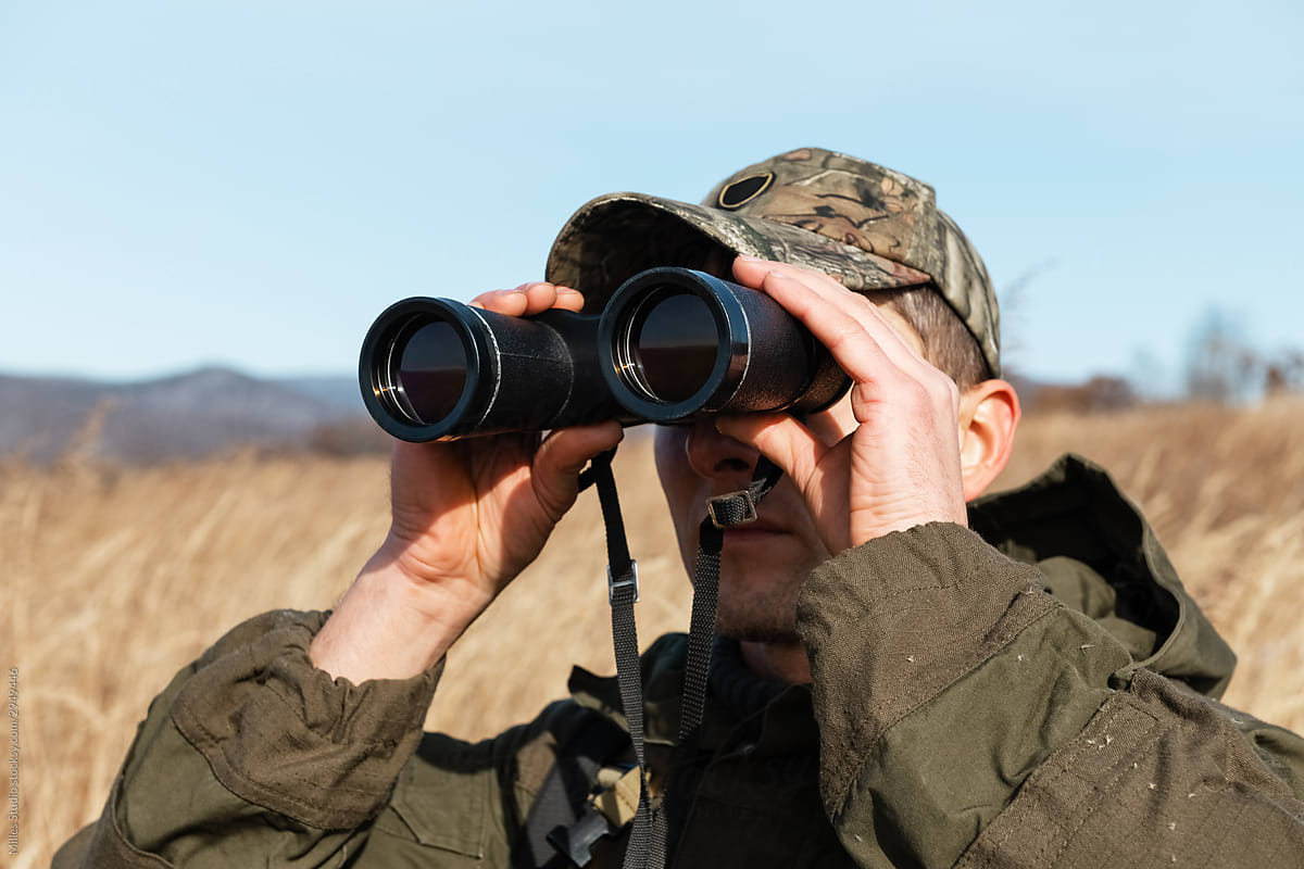 Focused hiker with binoculars exploring countryside