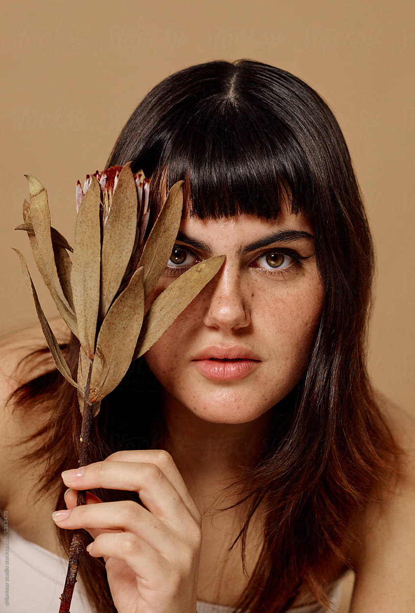 Beauty portrait of woman with powerful stare through big dried flower