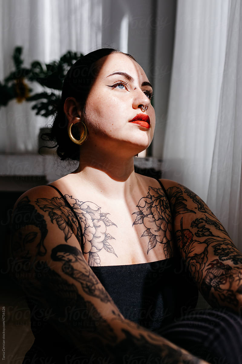 Attractive woman with tattoos in light room