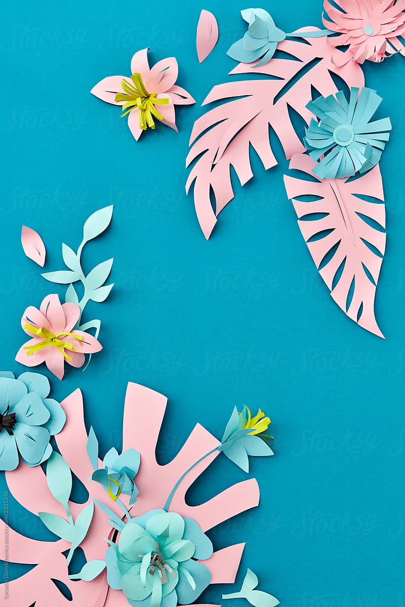 Handcraft creative decorative floral corner frame made of paper flowers and leaves, card for invitation with various leaves on a blue. Flat lay