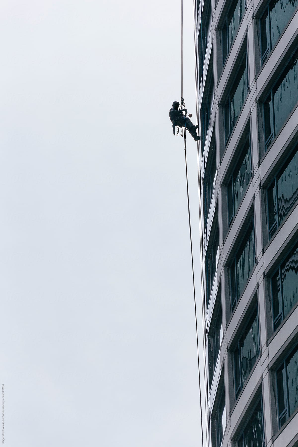 Window cleaner silhouette suspended on a rope on a building