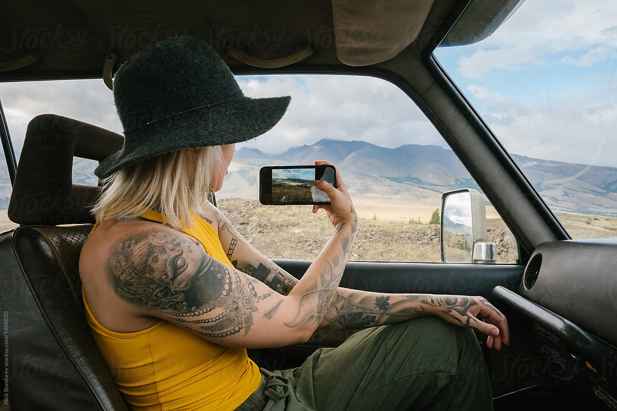 Anonymous young tattooed blonde woman sitting in the car