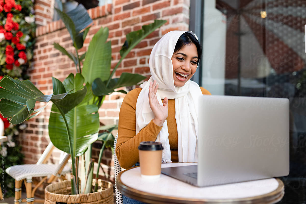 Muslim Woman Laughs While Waving at Laptop