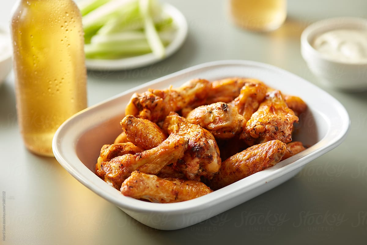 Spicy BBQ chicken wings with beer and vegetables.