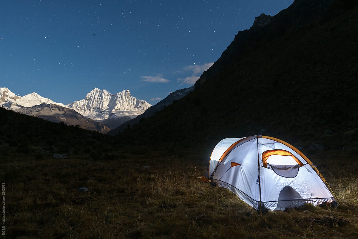 Lit tent under the night sky in the mountains