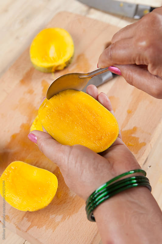 Hand of a south asian woman scooping up a mango