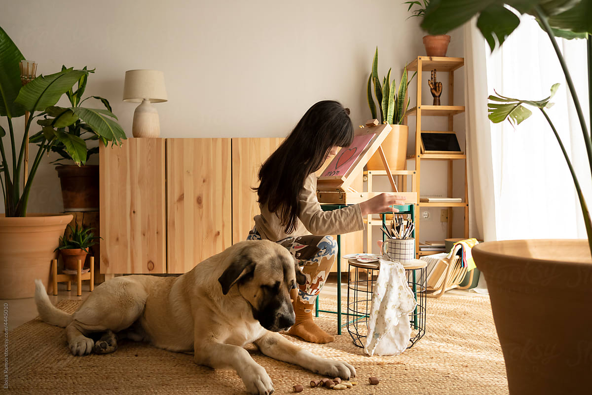 Girl painting with her dog at home
