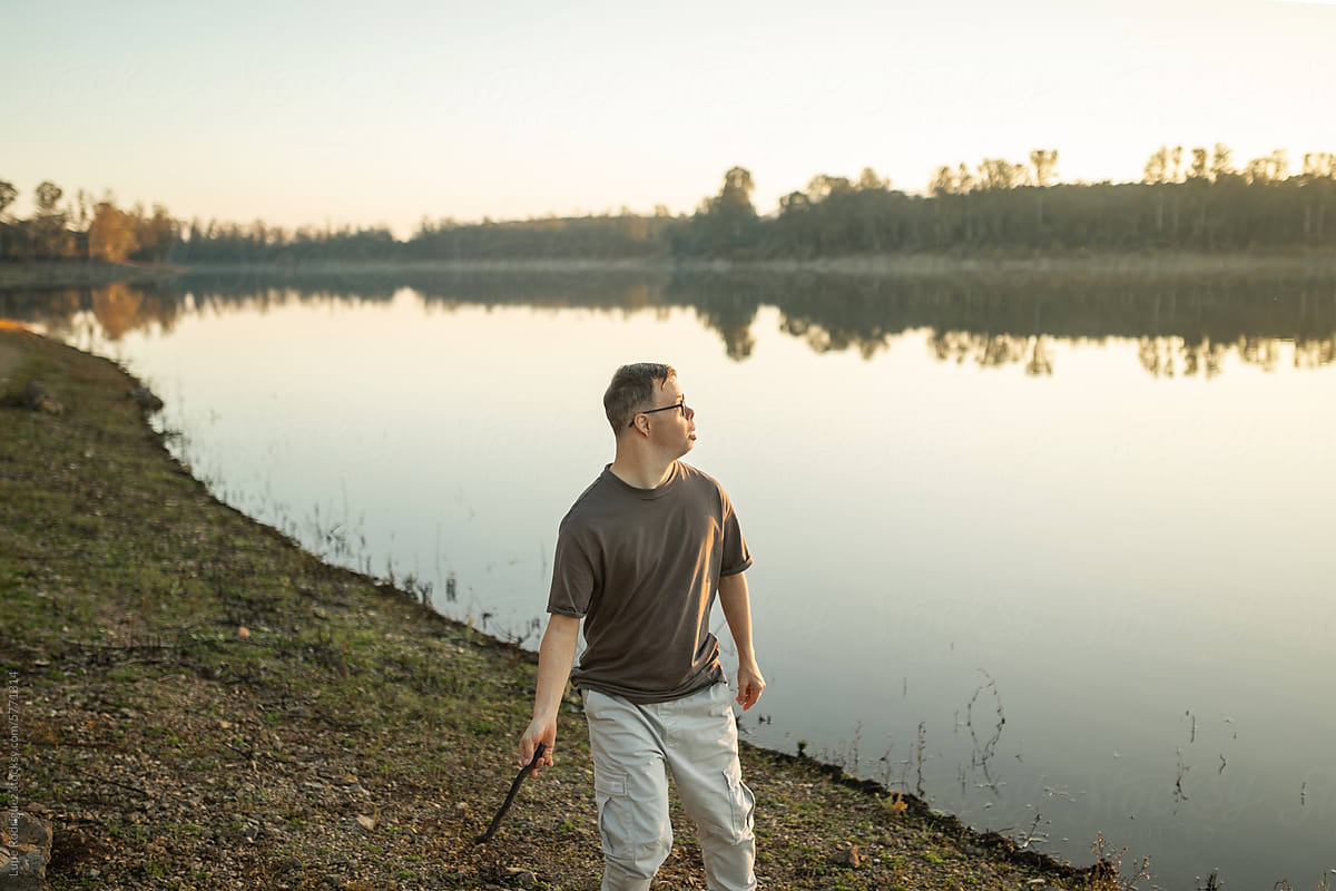 man with down syndrome next to a river in nature
