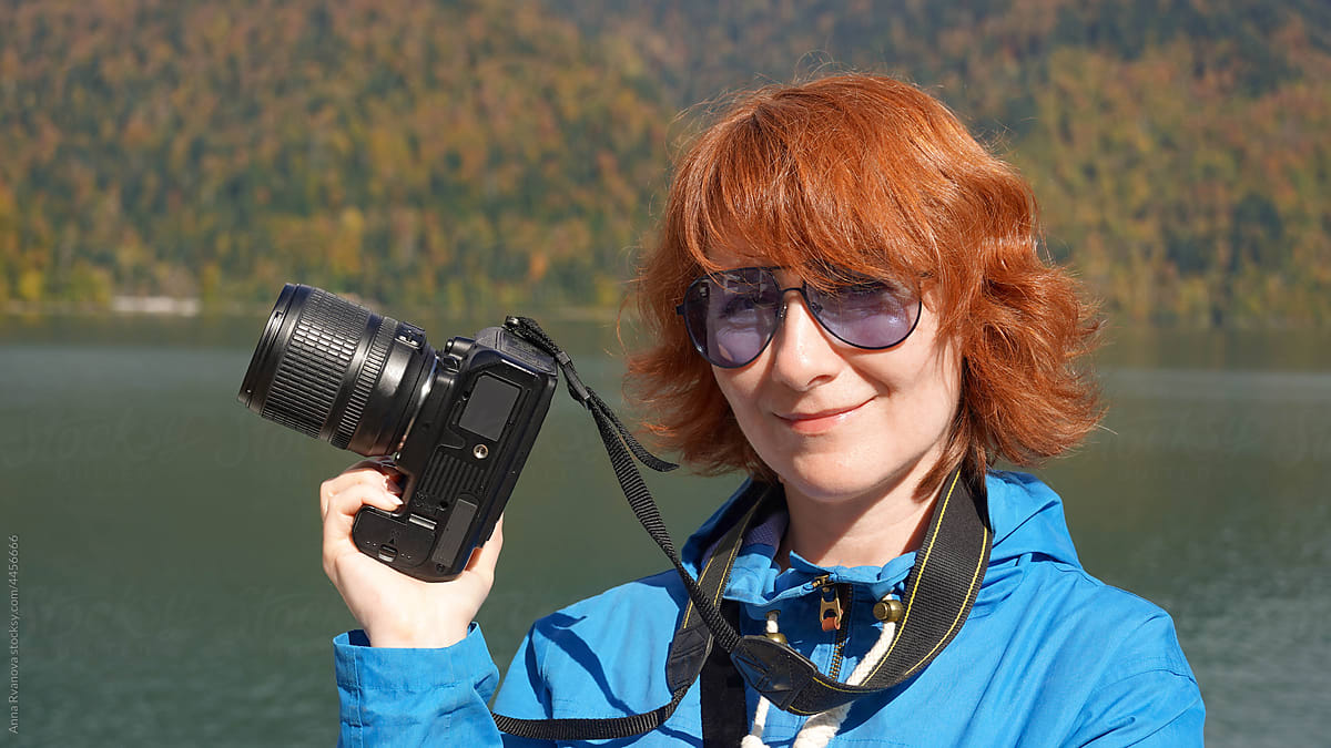 red-haired woman photographer on the background of lake