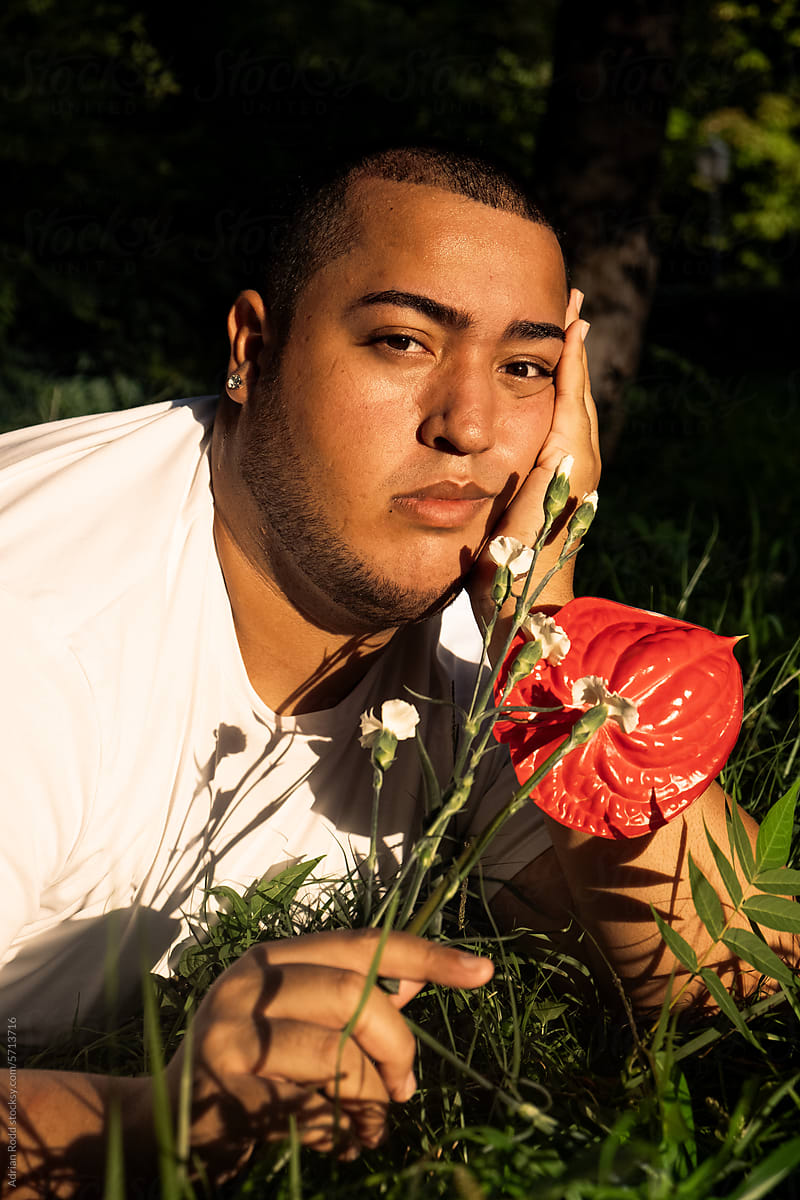 Portrait of plus size black boy with red and white flowers in hand.