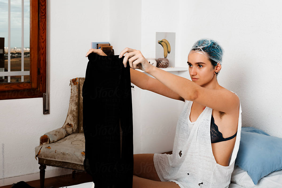 Androgyne woman choosing outfit at bedroom