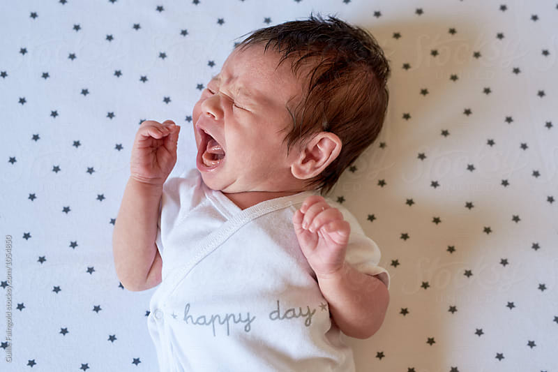 Crying newborn baby on printed star sheet
