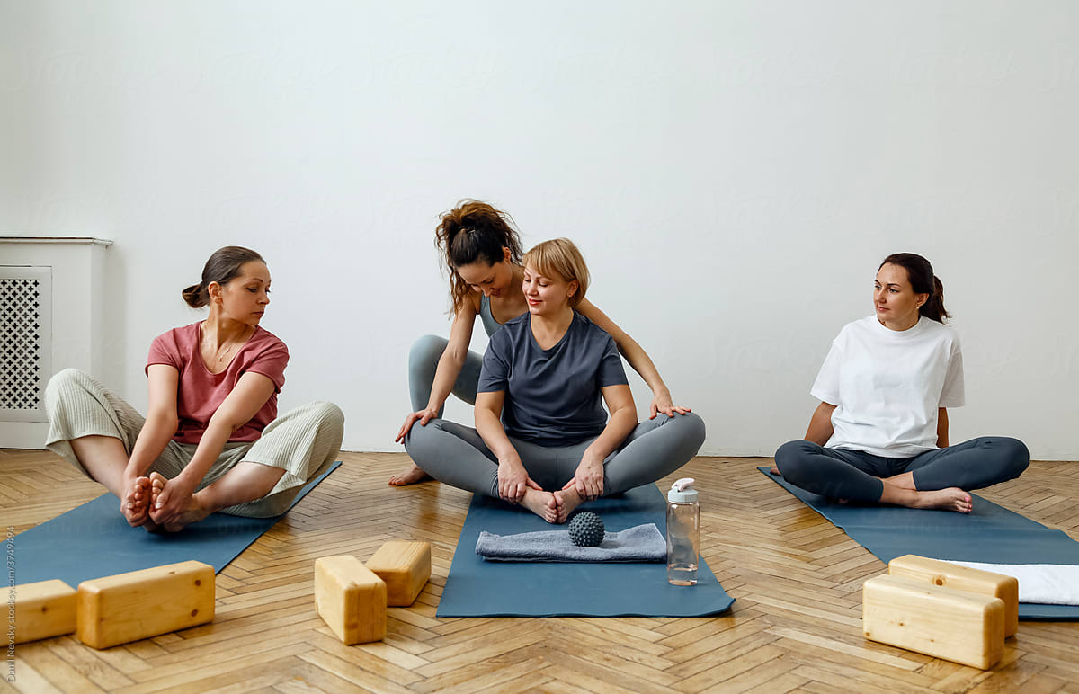Group of women doing yoga under control of instructor
