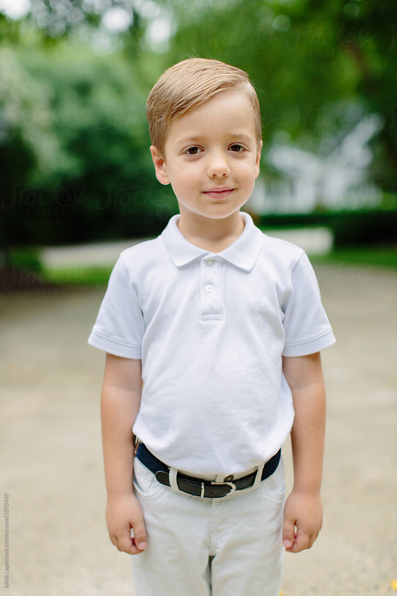 Portrait of a cute boy in a white polo shirt and white pants