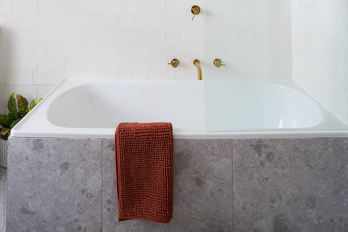 Large bath tub with ochre colour towel