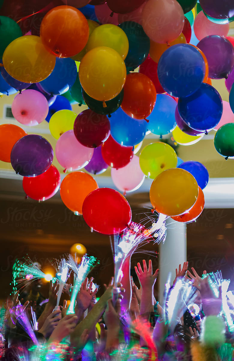 Hands reach to the sky at balloons falling from the ceiling at New Year\'s Eve party.