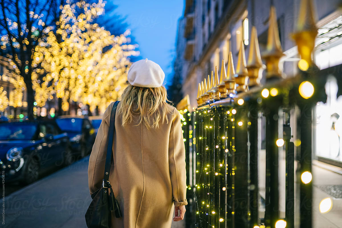 Woman in outerwear walking on street with garlands