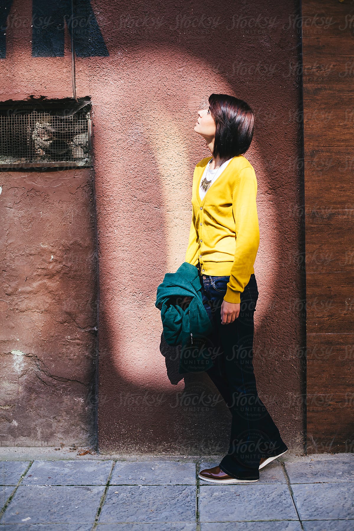 Young woman with yellow jacket and green coat in urban environment