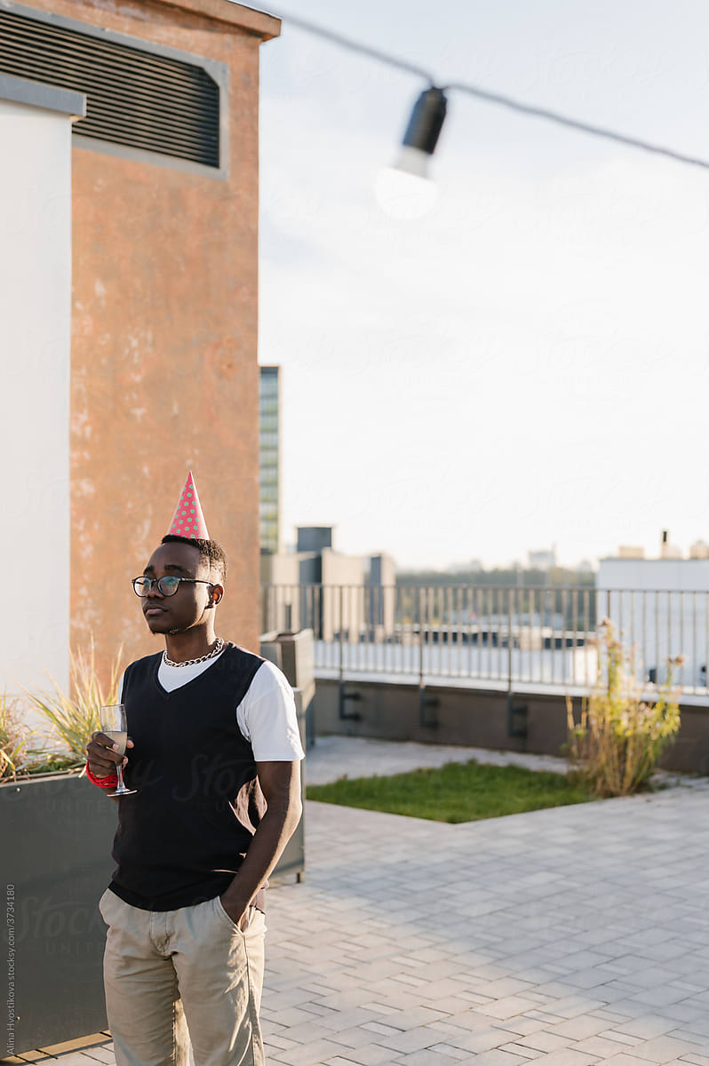 Sad Black Man In Party Hat On Terrace 