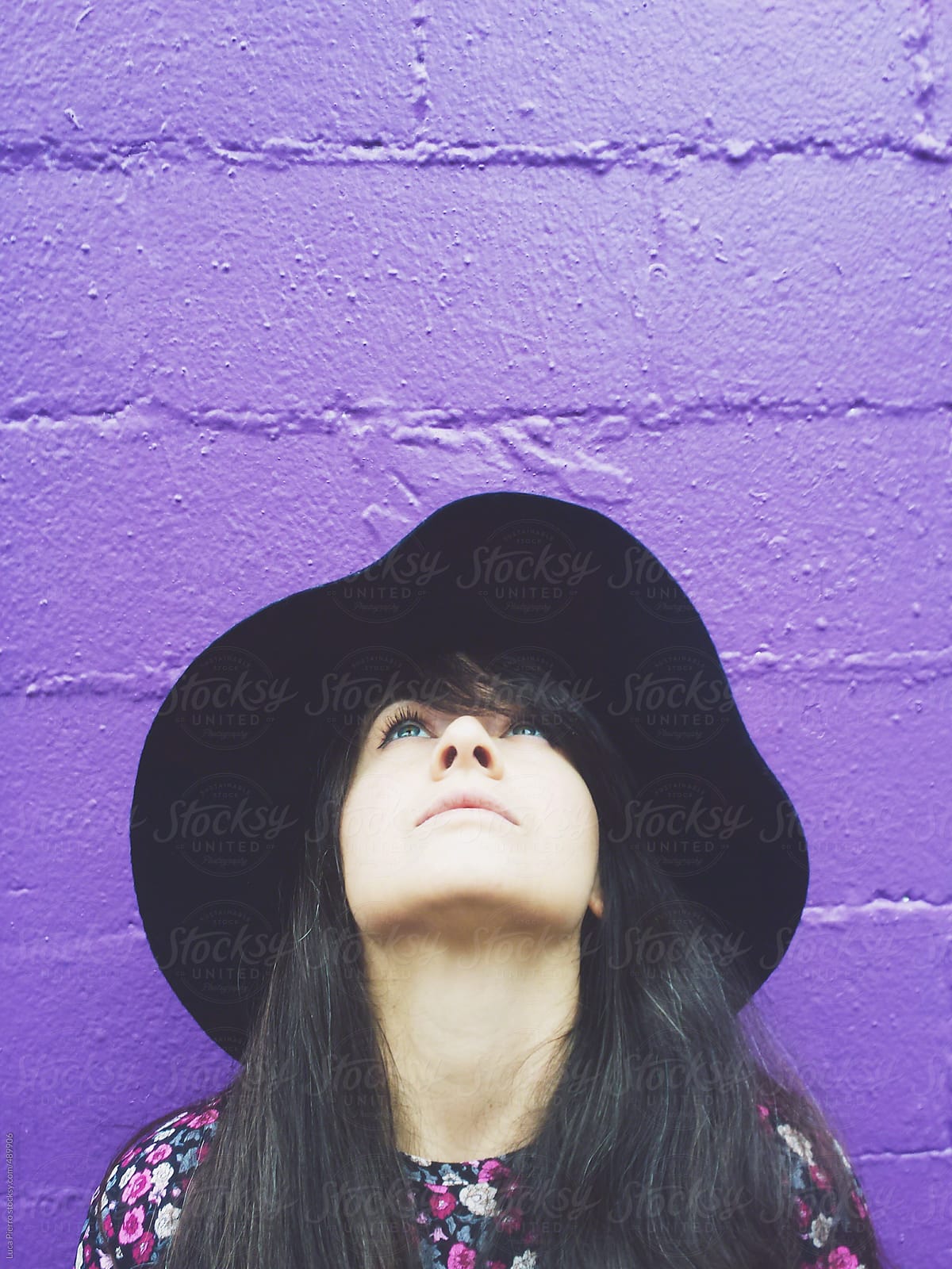 Woman against a purple wall looking up