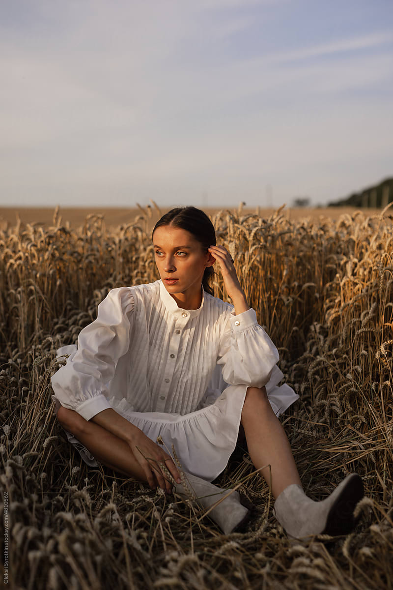 Female model taking break among wheat field