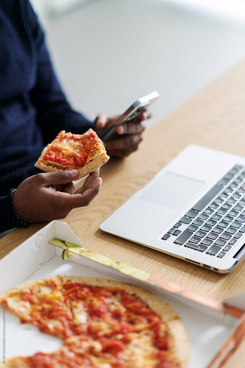 Remote worker eating pizza for lunch at workplace