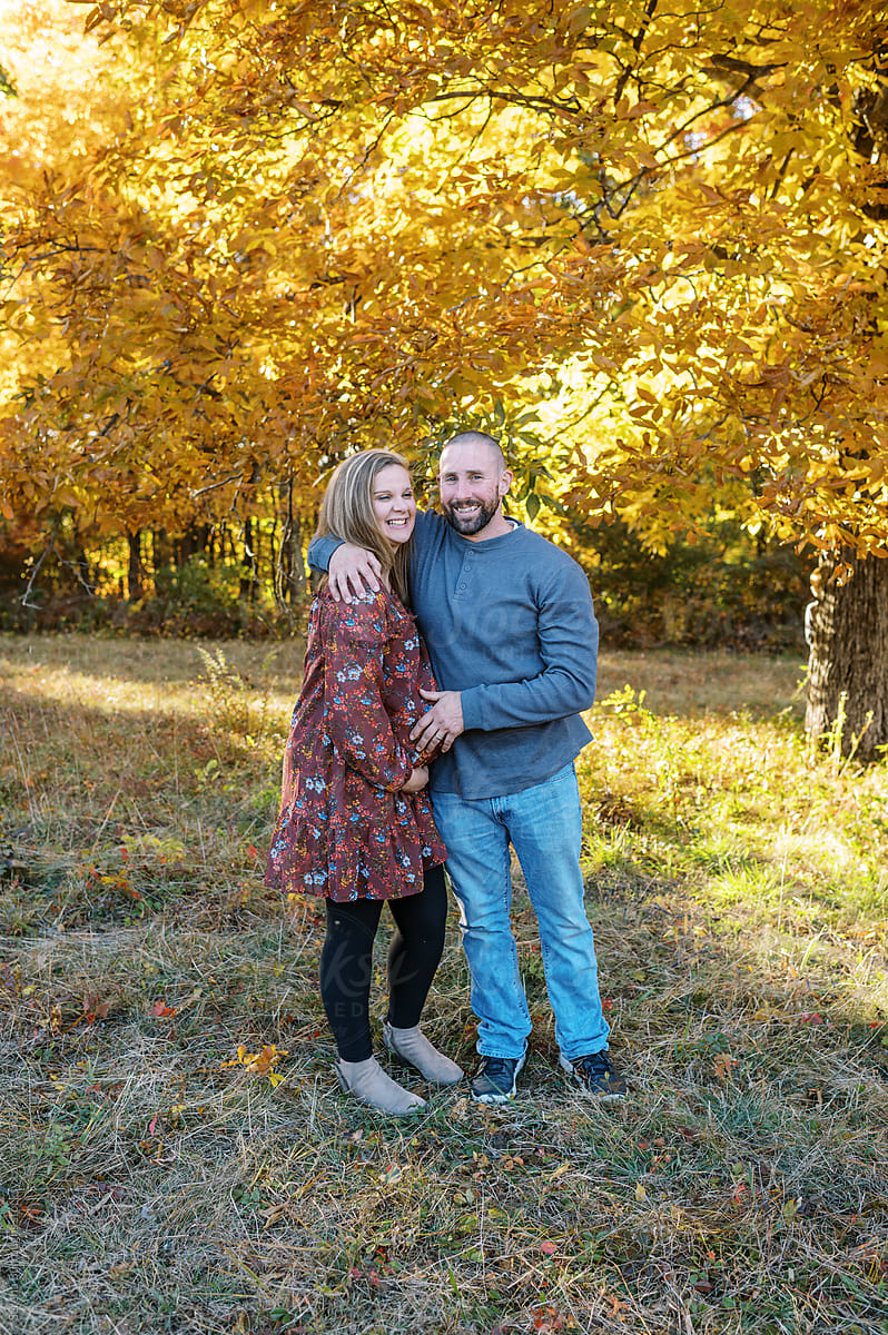 man and pregnant woman hugging outdoors in fall
