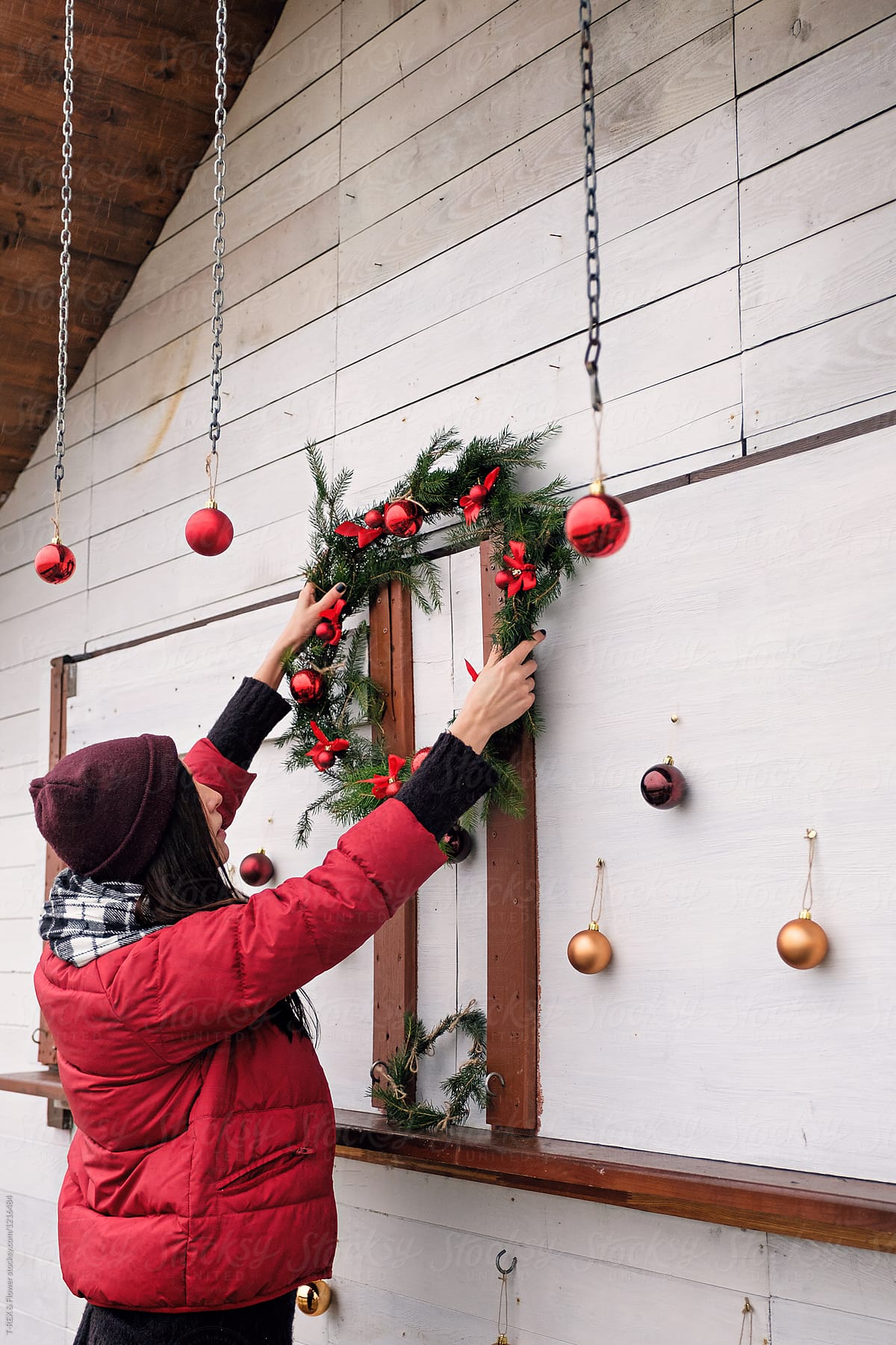 Girl in coat hanging Christmas wreath