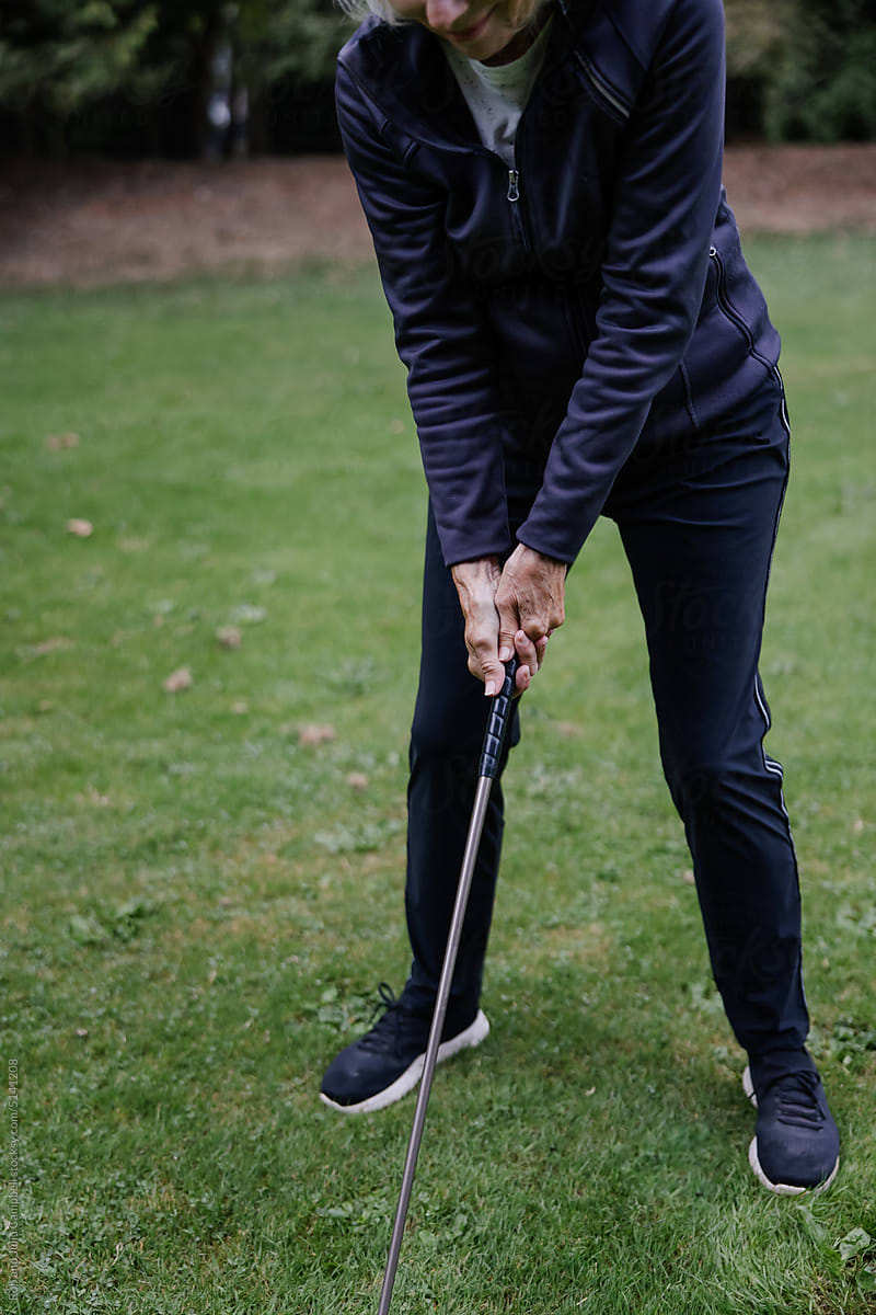 Silver haired woman playing golf on course.