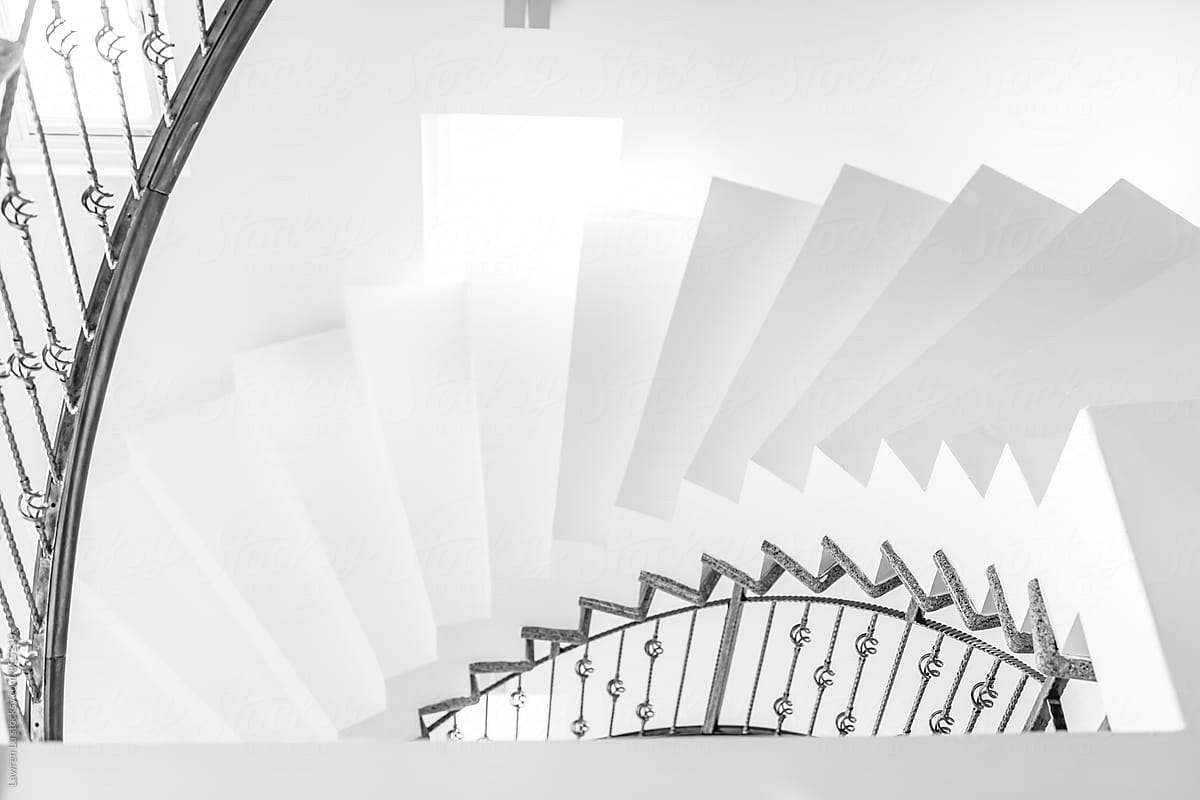 White internal spiral staircase with iron railing in building interior
