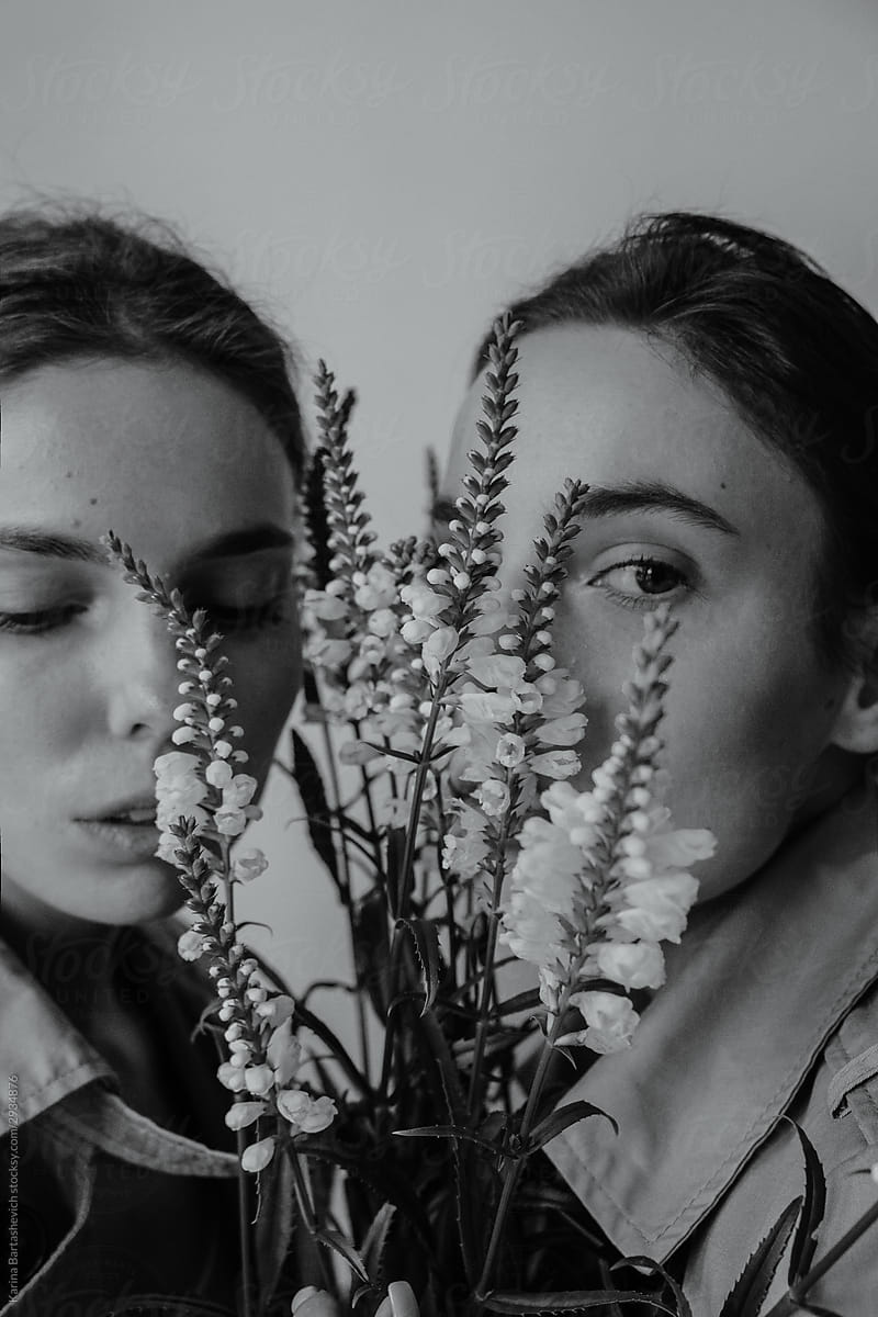 black and white portrait of twin sisters whose faces cover the branches of a bouquet of flowers