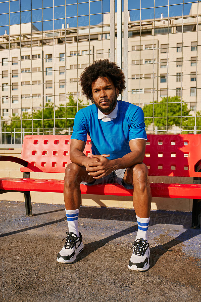 Confident football player sitting on bench