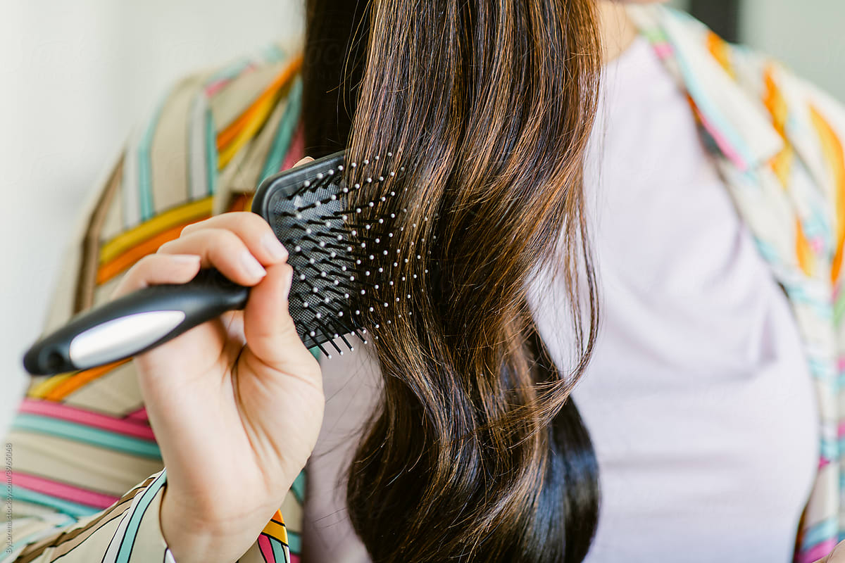 Unrecognizable woman brushing long dark hair