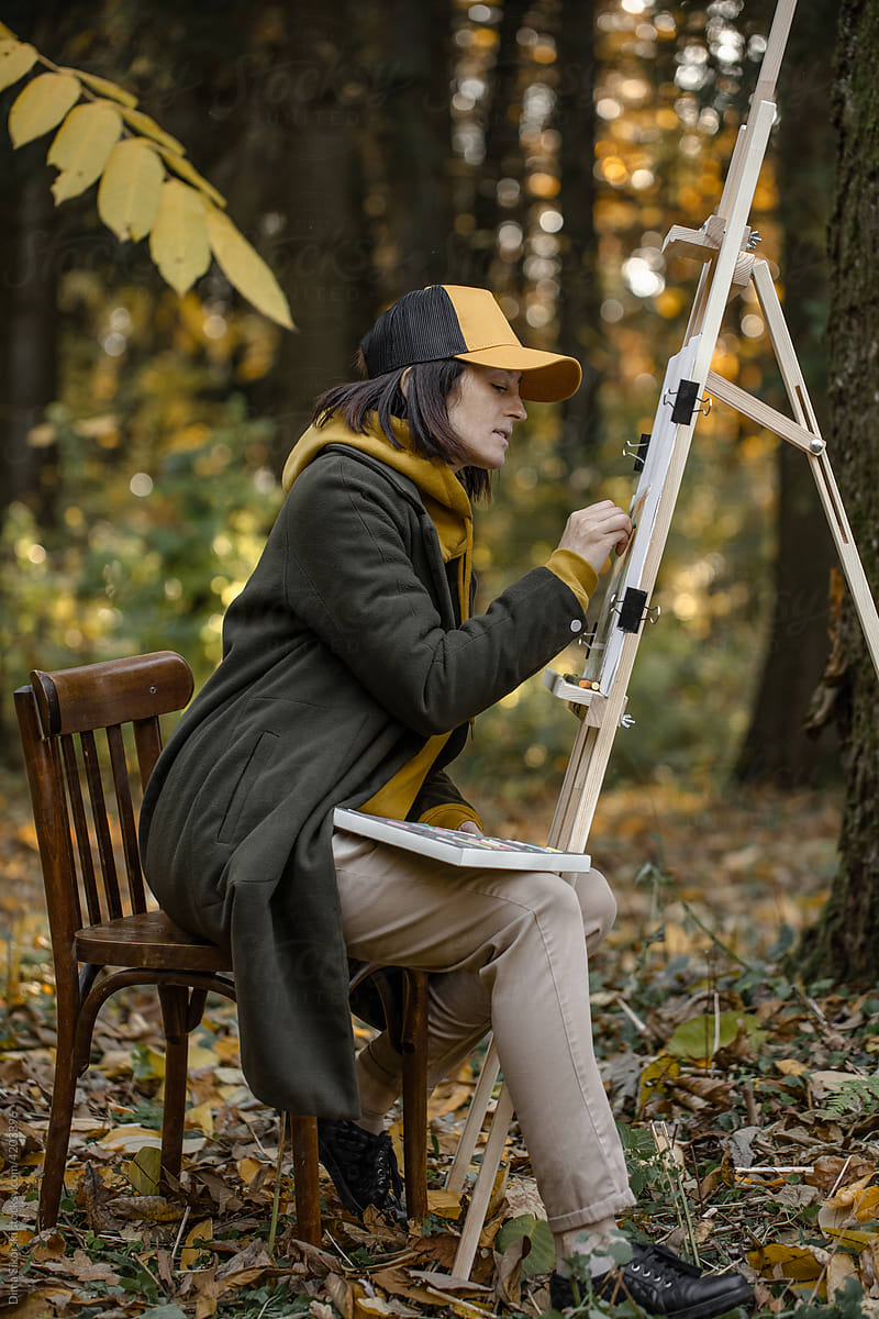 the painter paints en plein air in the forest