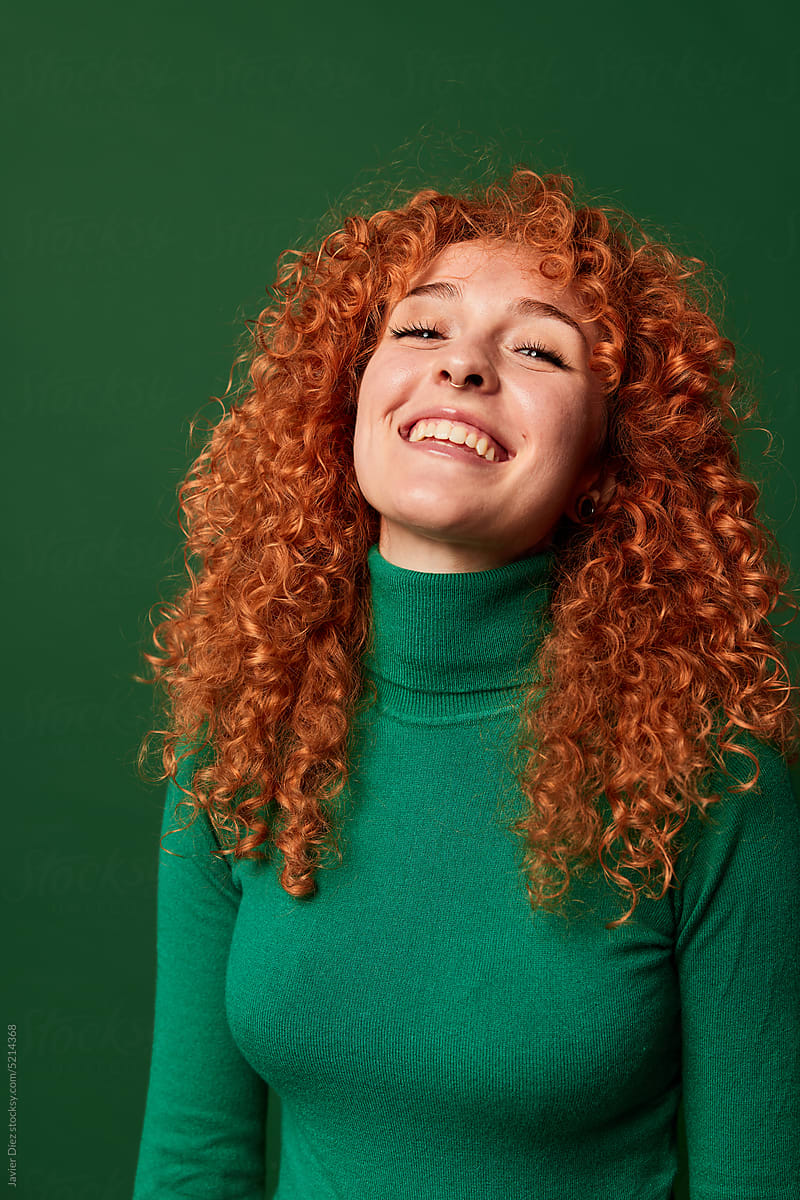 Smiling ginger woman on green background