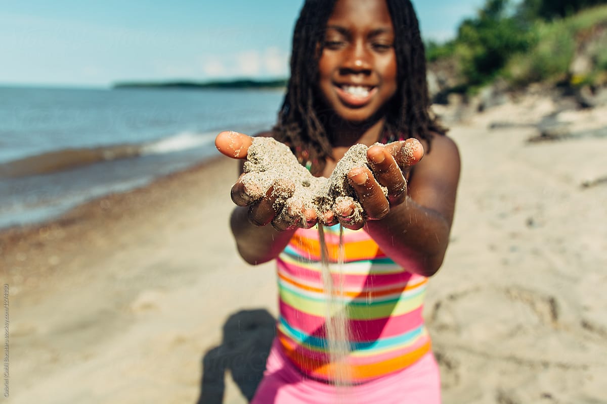 Smiling Black Girl Playing With Sand At The Beach By Stocksy Contributor Gabriel Gabi