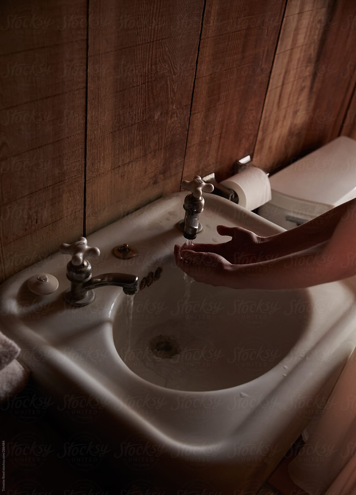 Woman washing her hands in rustic wood cabin bathroom