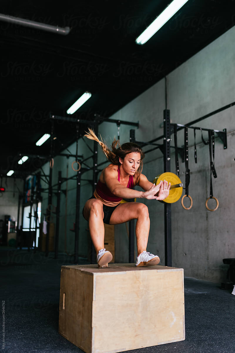 Fit young woman box jumping at a crossfit style gym.