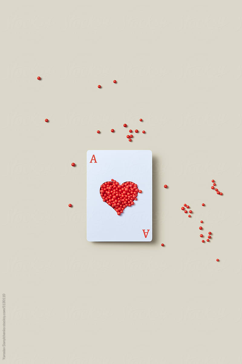Ace card with red spheres in heart opening.