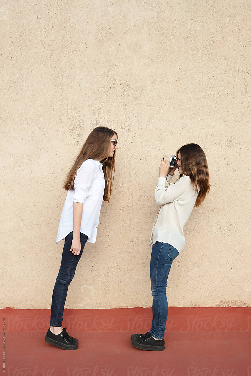 Fun scene of two female teenagers photographing themselves.