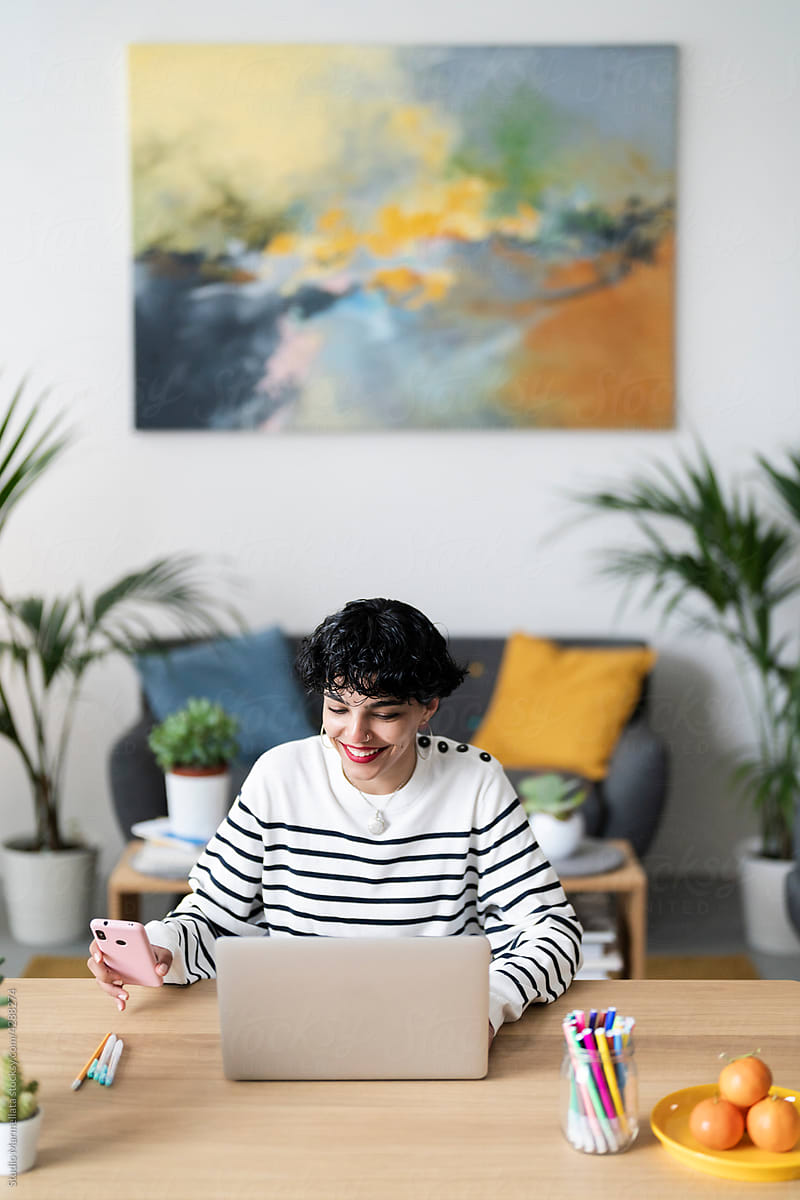 Cheerful woman browsing gadgets in home office