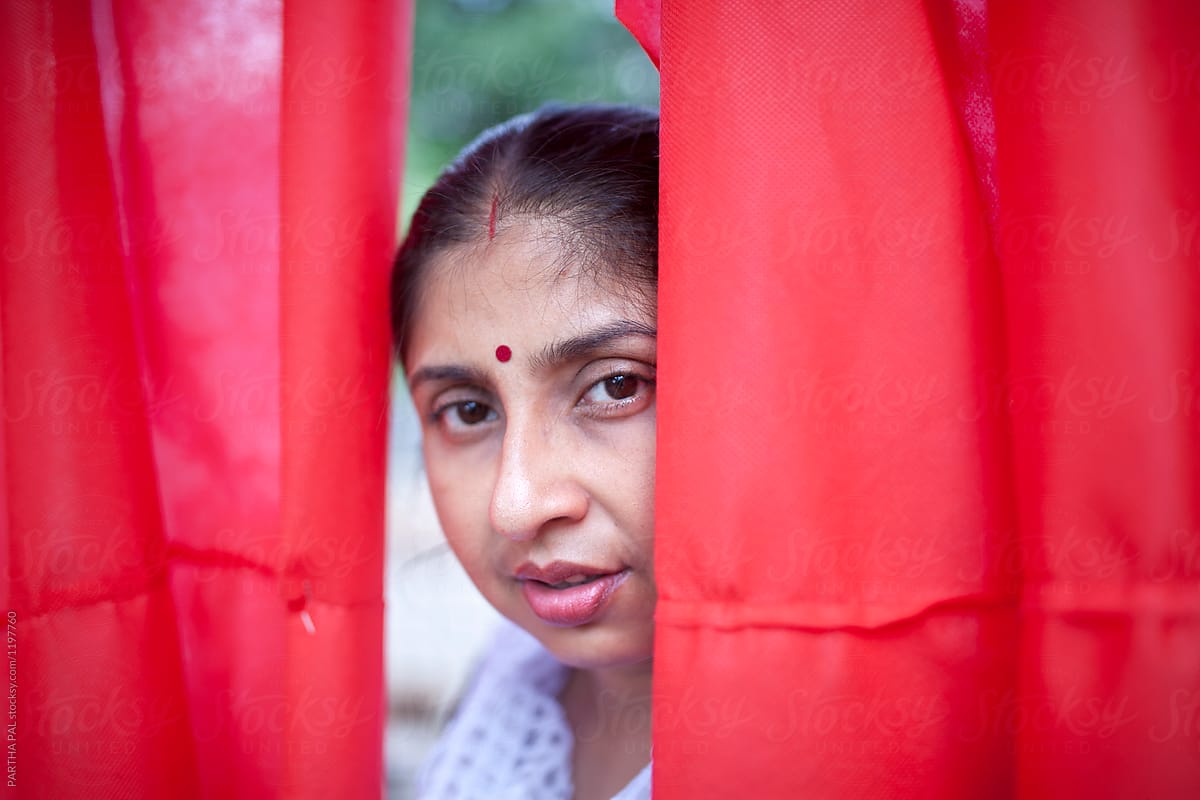 Happy Indian Woman Peeping Through Red Curtain Del Colaborador De Stocksy Dream Lover Stocksy 