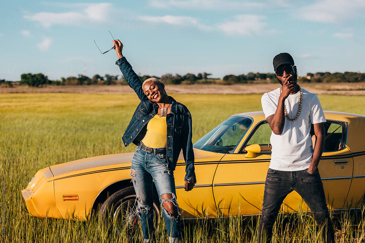 Stylish couple posing in the countryside besides a classic car